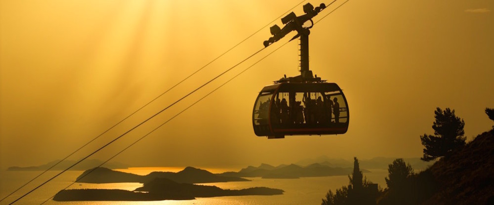 The Dubrovnik cable car silhouetted against a golden sky, the islands below.