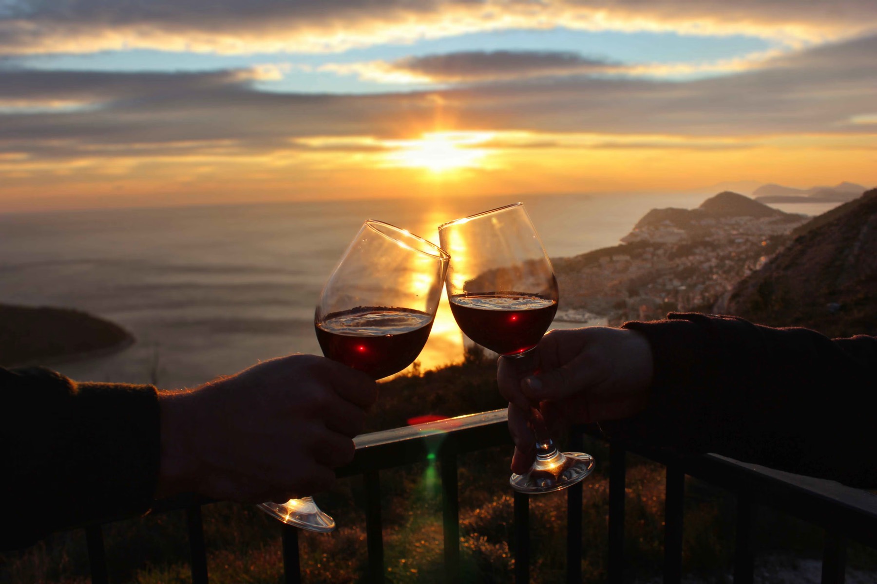 Two glasses raised against the sea at sunset from the terrace.